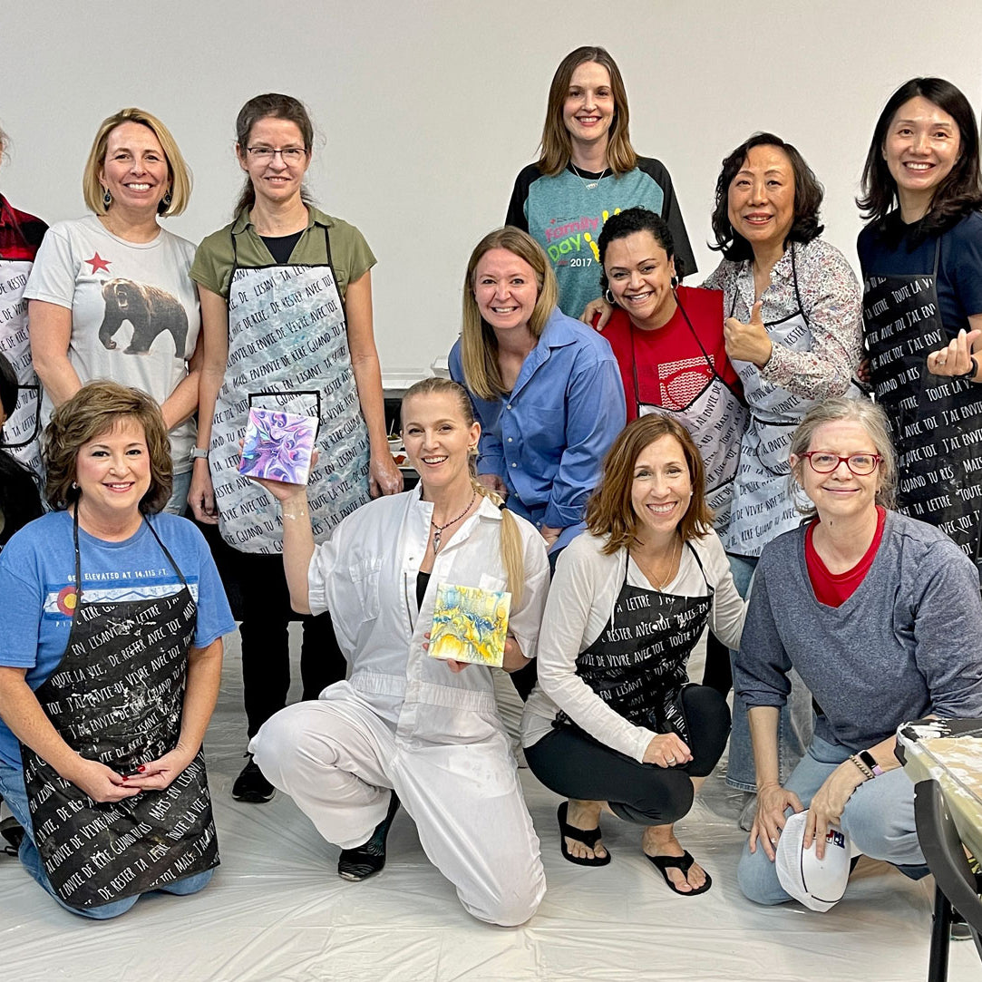 Team-building workshop participants pose for a group picture with Anja Yamaji, who is holding up her acrylic flow paintings.