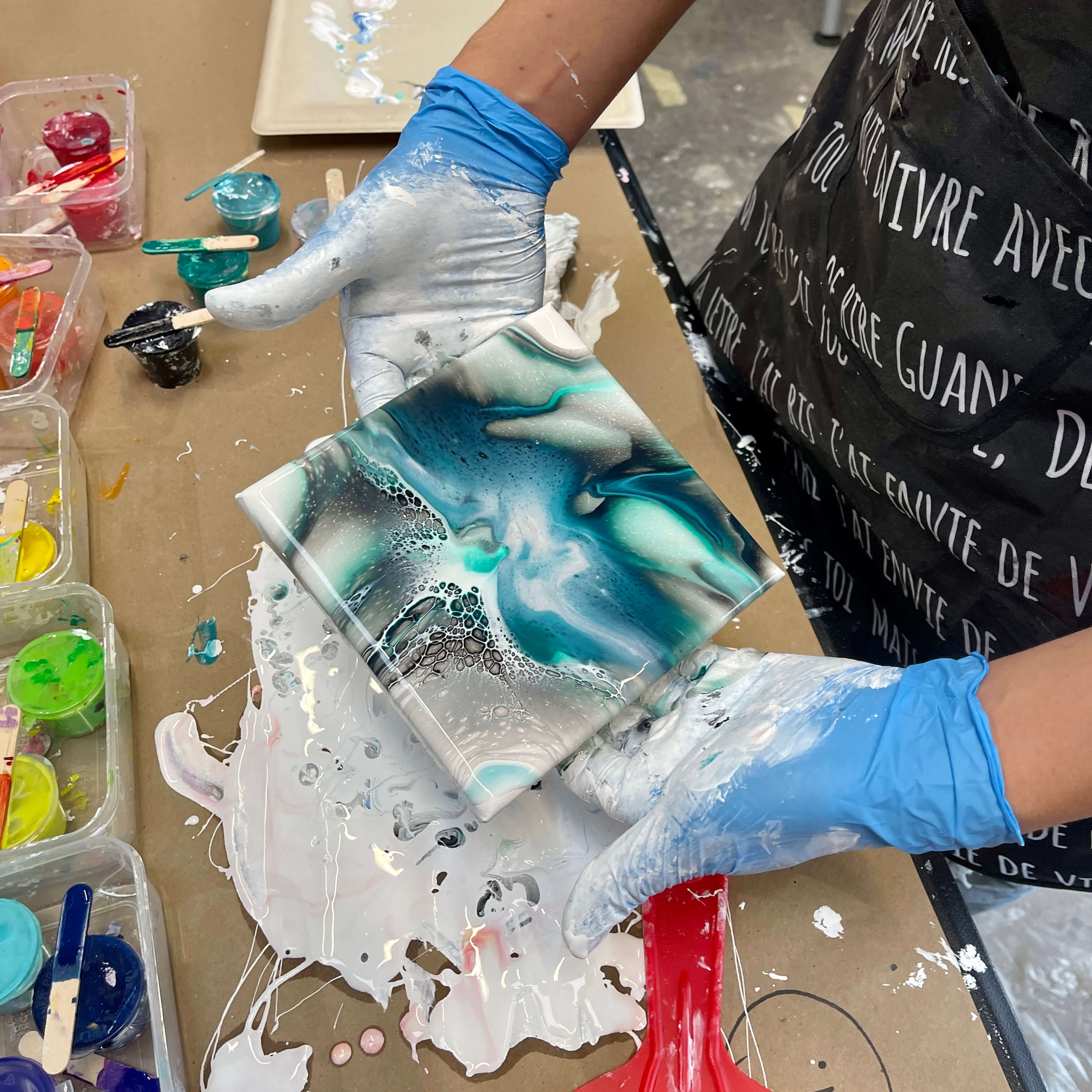 Close-up of a student's vibrant acrylic flow painting with gorgeous cells and lacing, right after the tilting process.