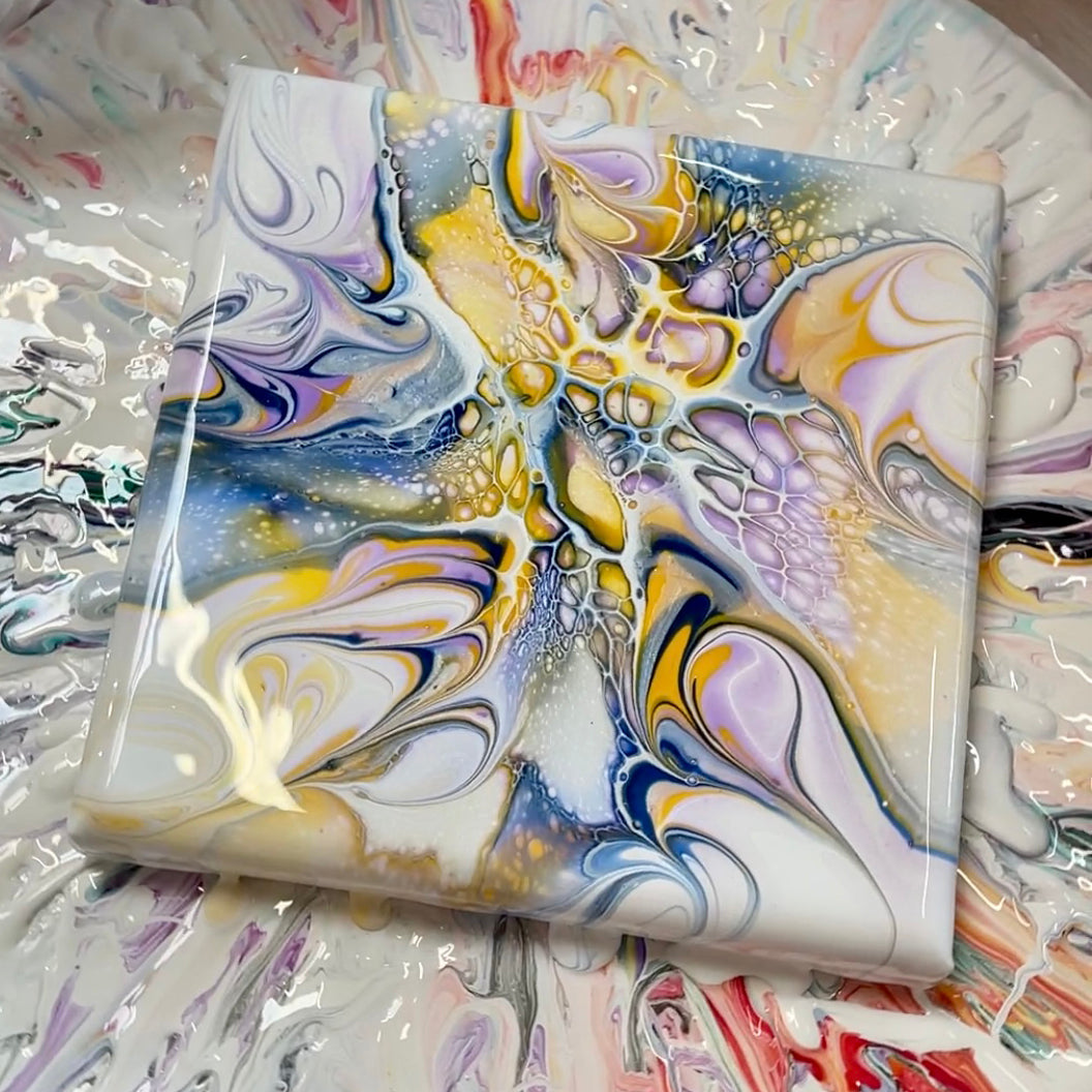 Close-up of a colorful acrylic flow painting on a turning table, showcasing stunning cells and lacing effects.