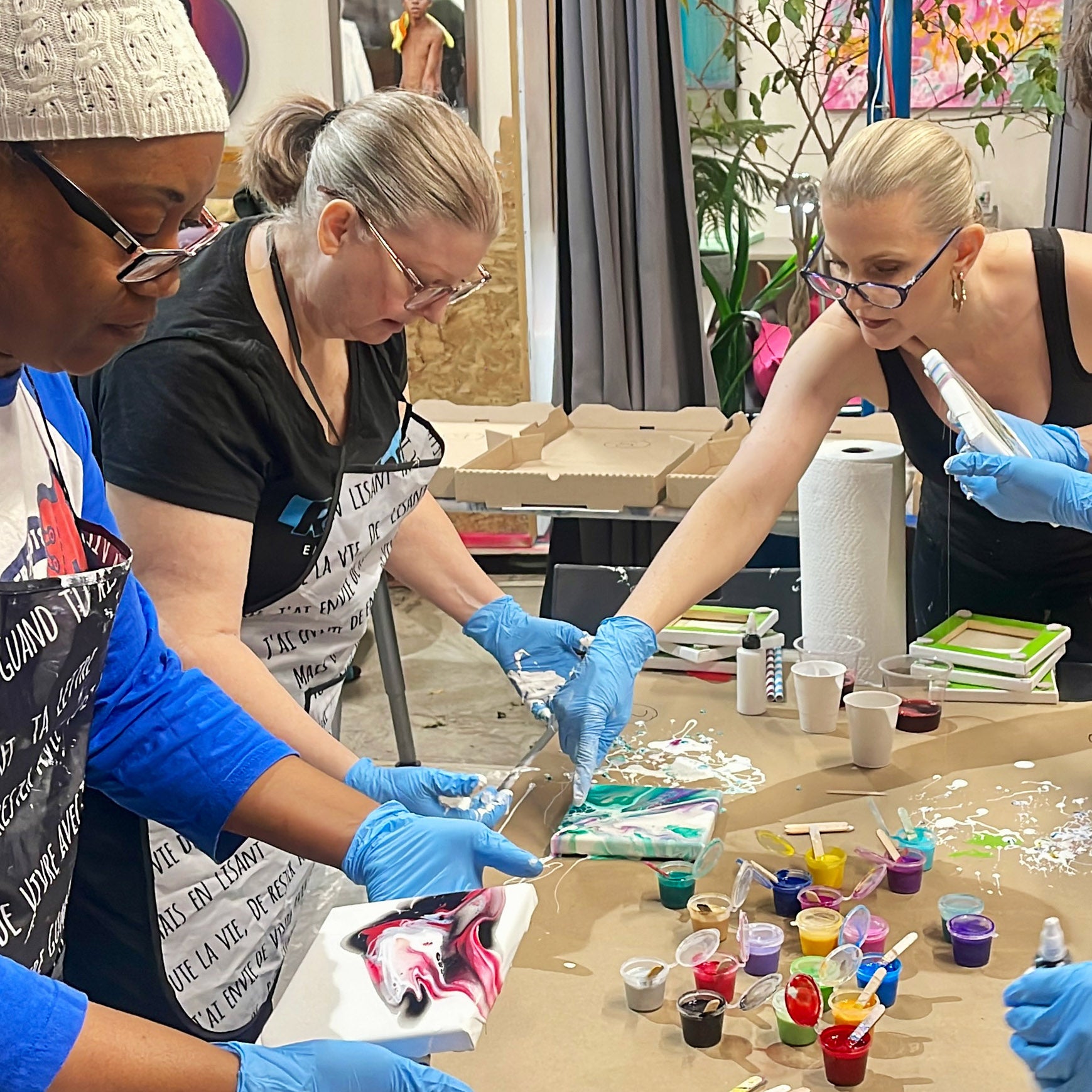 Anja Yamaji provides hands-on assistance to students as they create their paintings during an acrylic flow art experience.