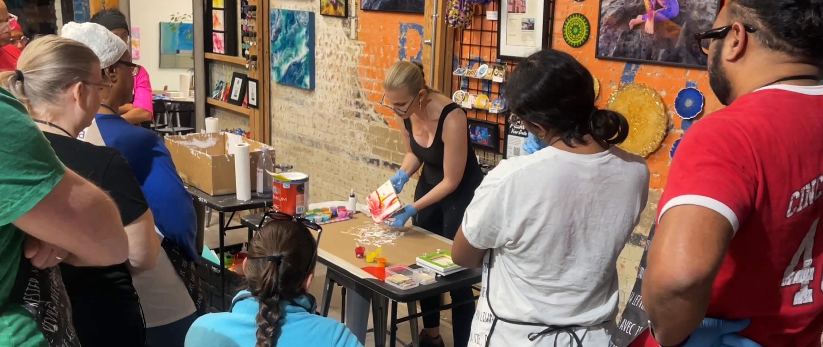 Anja Yamaji facilitating an acrylic flow art experience, doing a demo at her station surrounded by attendees watching.